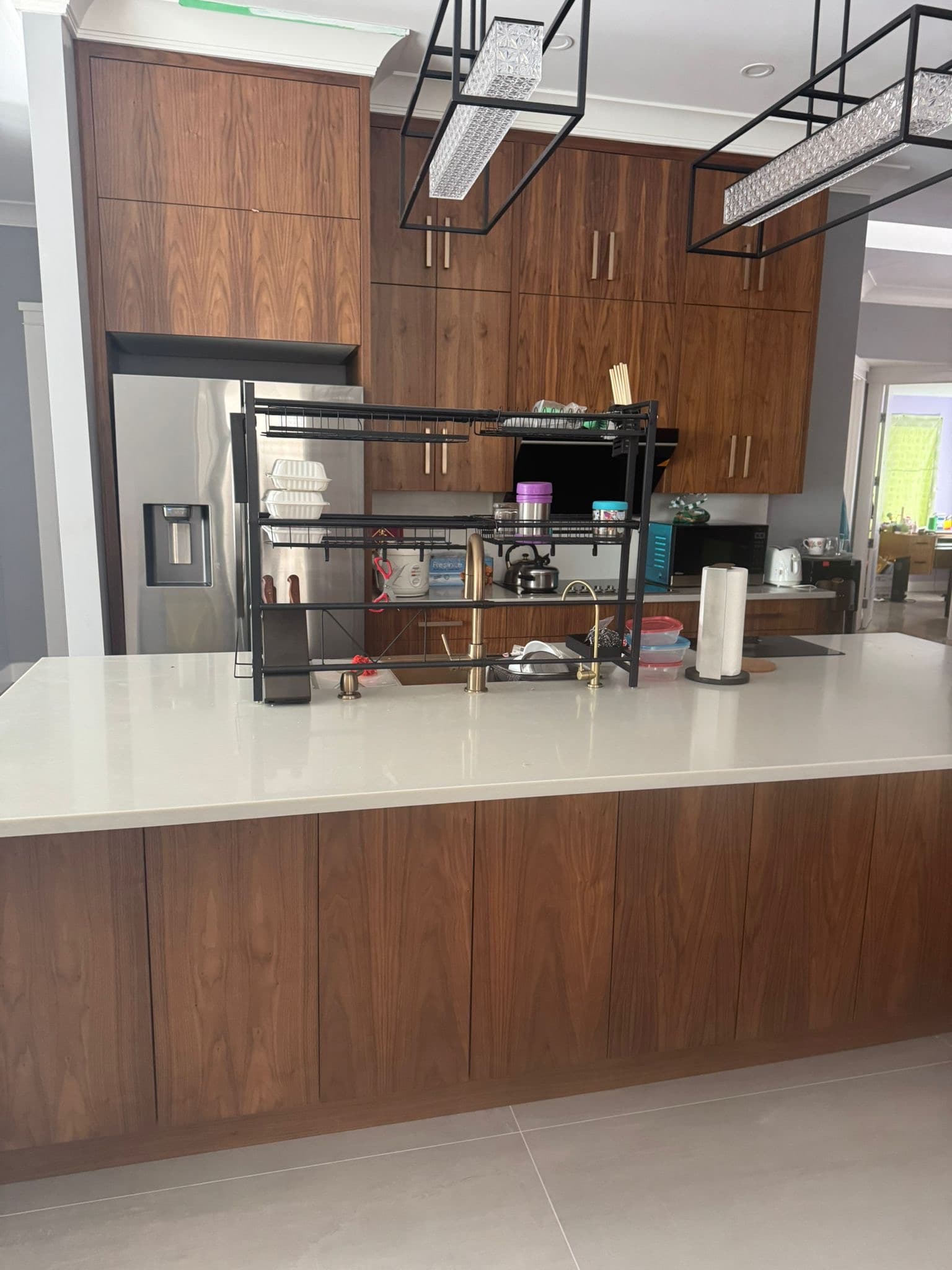Kitchen with tall dark wood grain cabinets, large white island, and stainless steel refrigerator. Calgary custom cabinets.