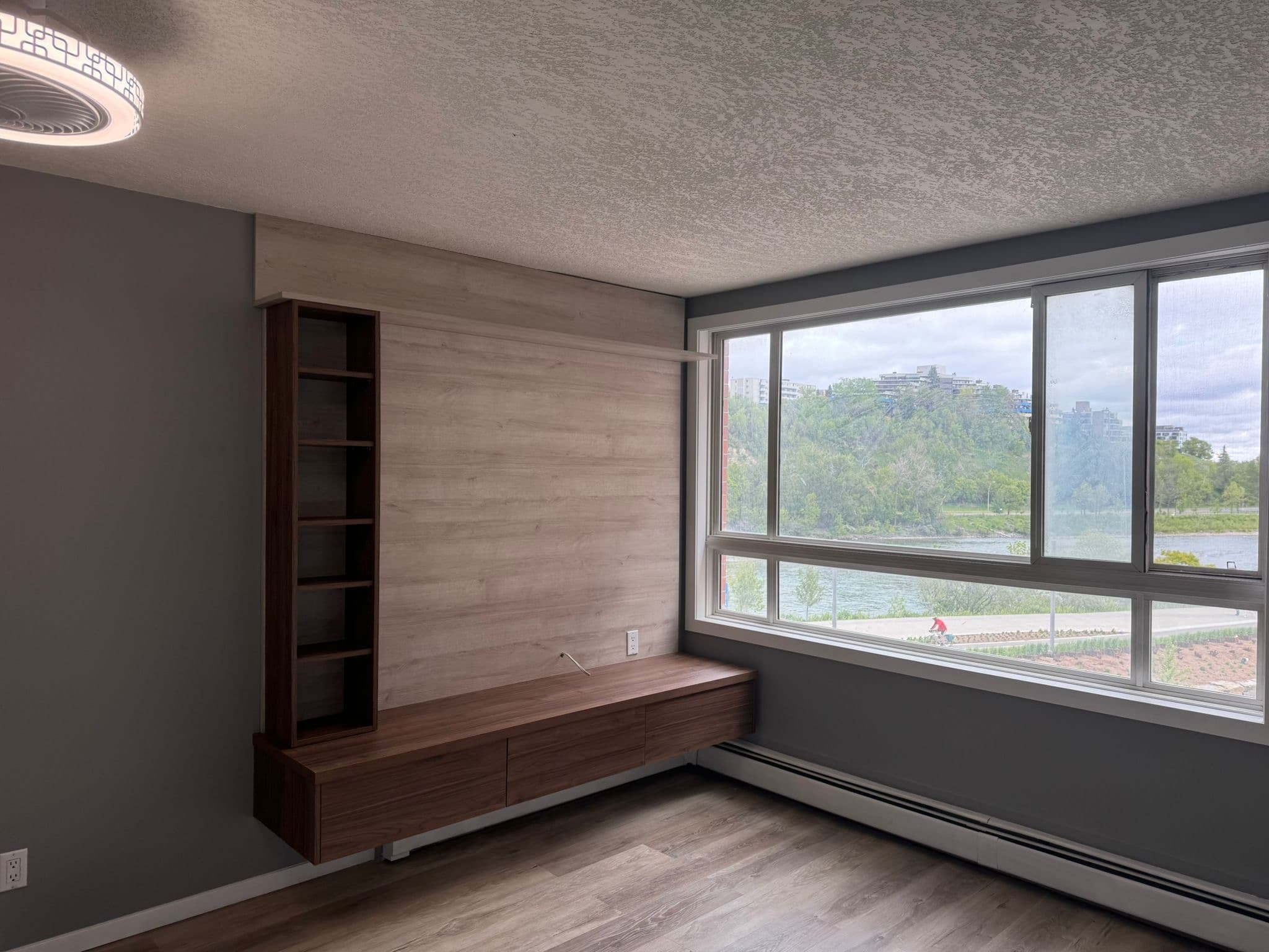 Living room with custom built-in media console and shelving unit in dark and light wood. Calgary custom cabinets.
