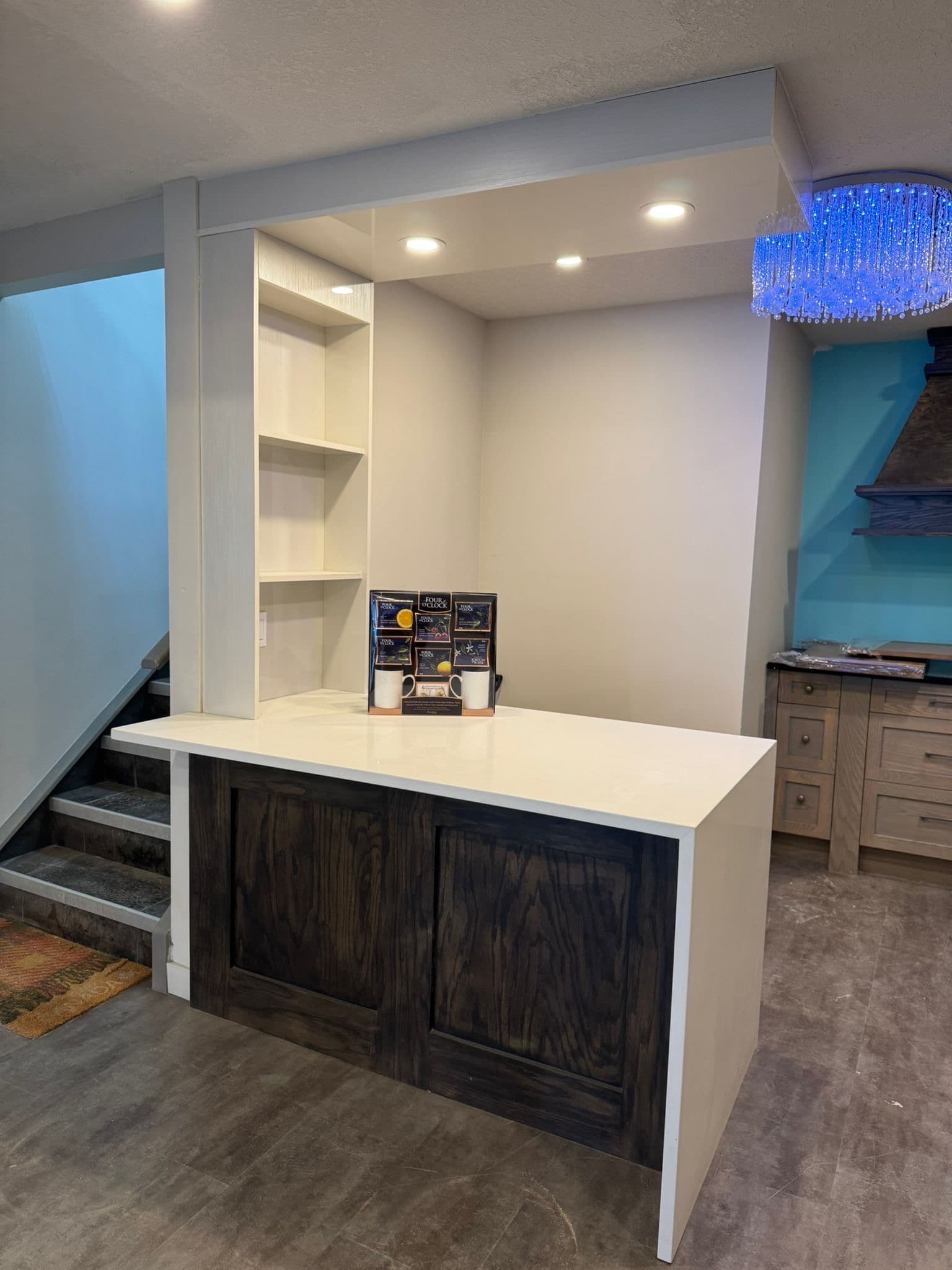 Custom bar area with white countertops, dark wood Calgary custom cabinets, open shelving, and a unique blue chandelier.
