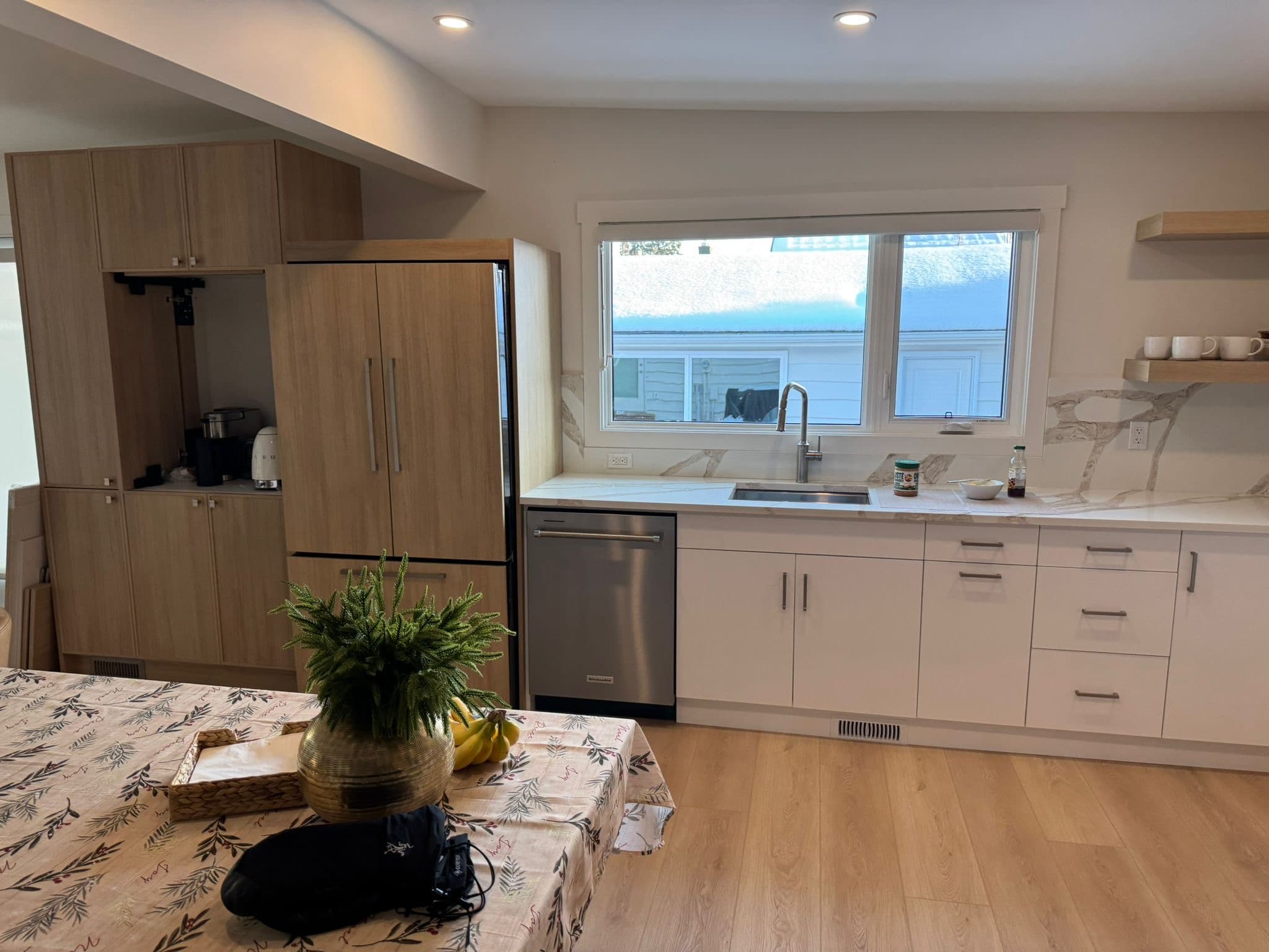 Contemporary kitchen with light wood flat-panel Calgary custom cabinets, integrated refrigerator, white quartz countertops, and light wood flooring.
