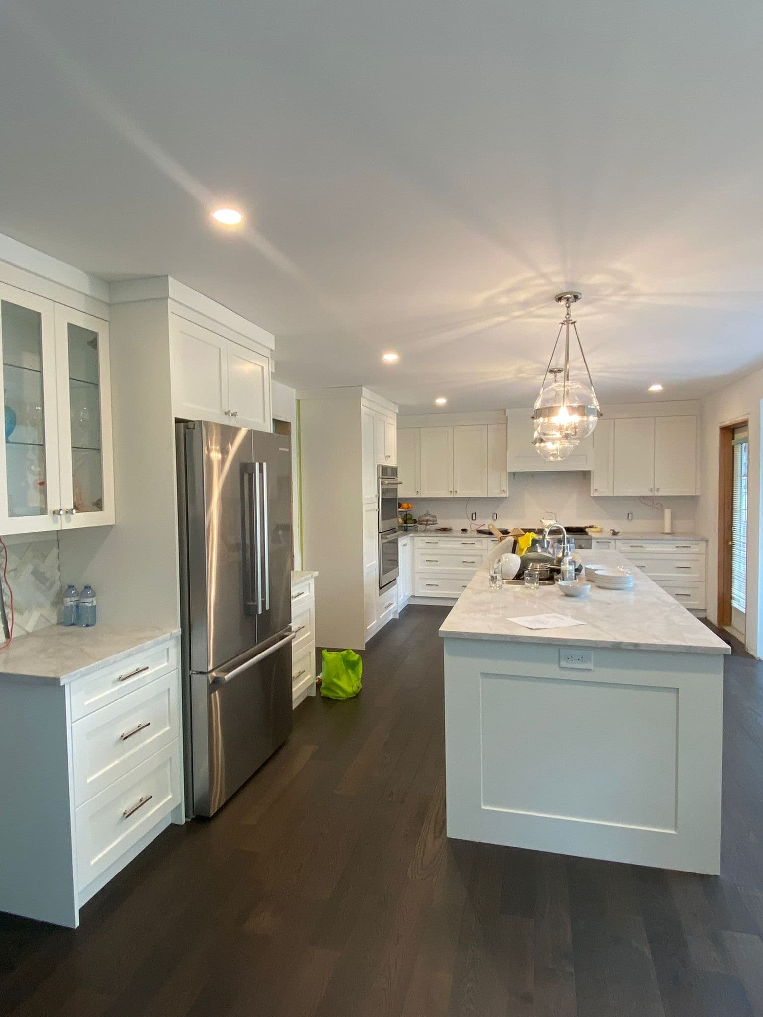 Traditional white shaker kitchen featuring Calgary custom cabinets, a large quartz island, stainless steel refrigerator, and pendant lighting.