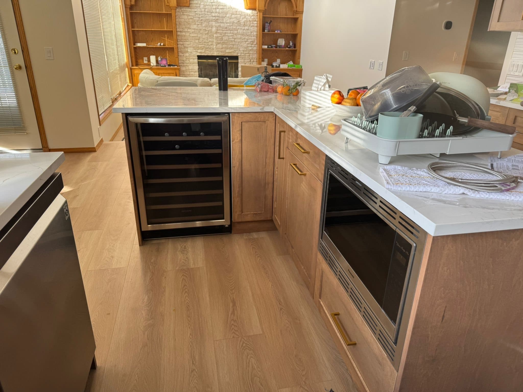 Kitchen island with natural wood custom cabinets, integrated wine fridge, microwave drawer, and quartz countertop, built by Calgary custom cabinets.